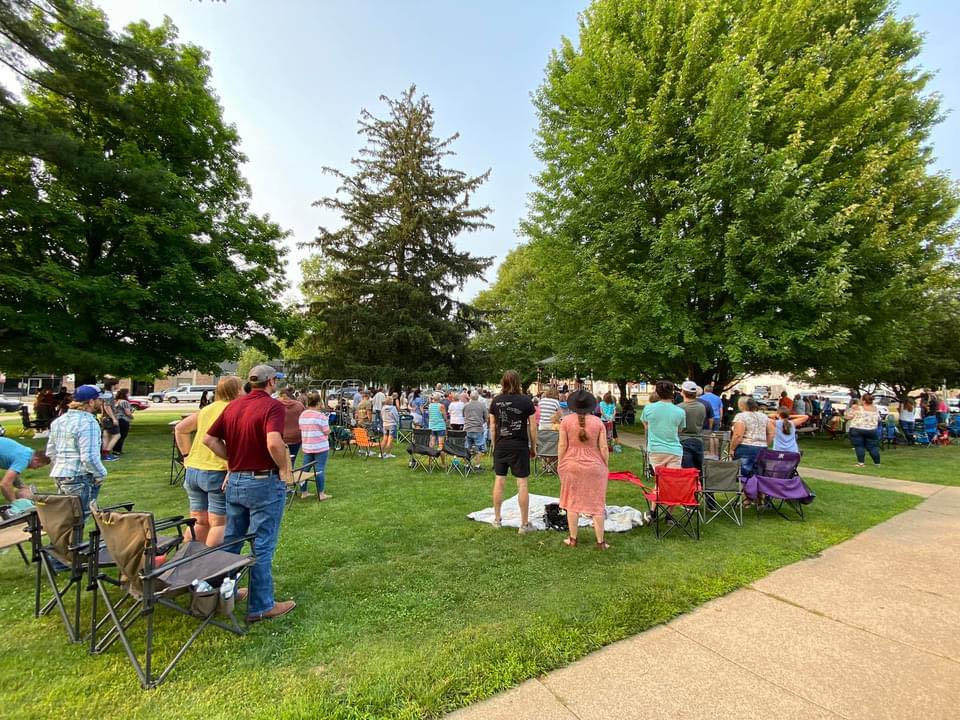 Community gathering in a park with chairs and trees.