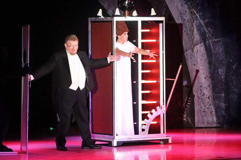Magician performs levitation trick on stage.