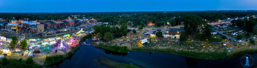 Aerial view of festival with river and lights.