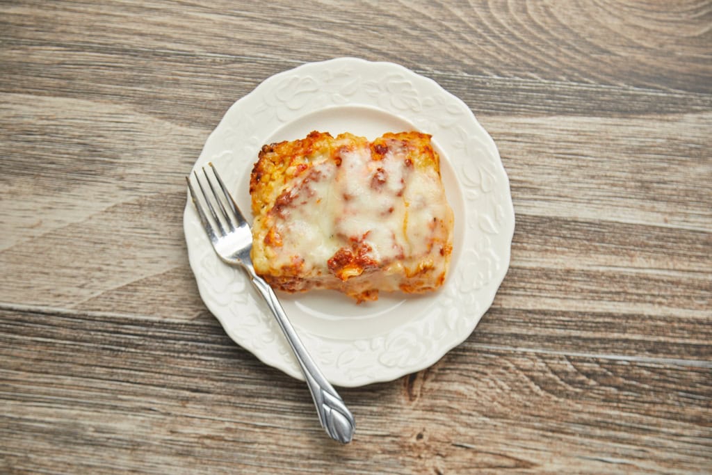 Square slice of lasagna on plate with fork