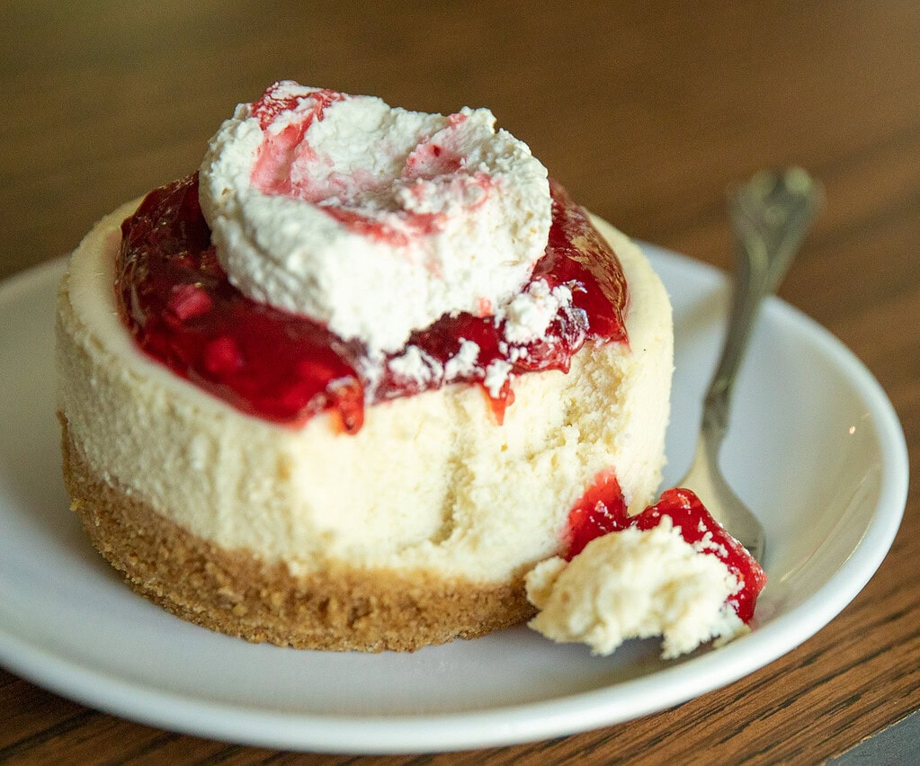 Strawberry cheesecake with whipped cream on a plate.