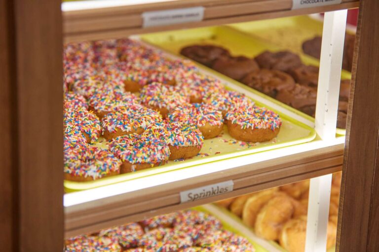 Tray of donuts with colorful sprinkles on display.