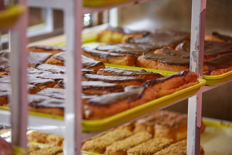 Chocolate eclairs displayed on bakery shelves.