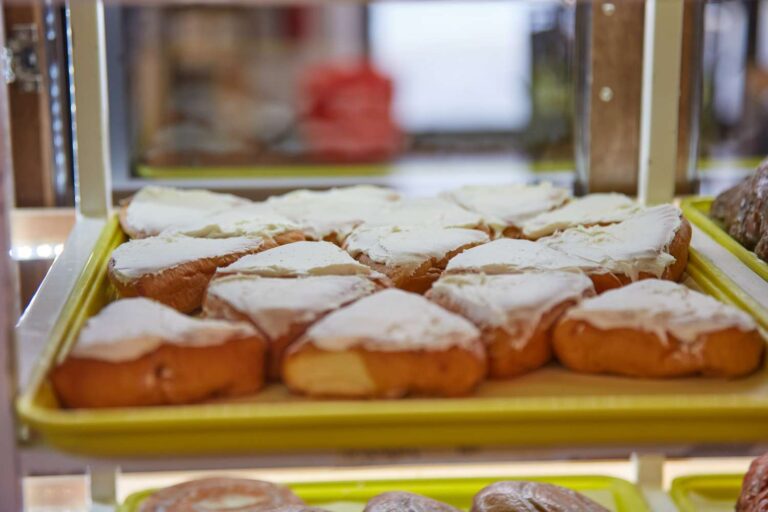 Tray of frosted pastries in bakery display.
