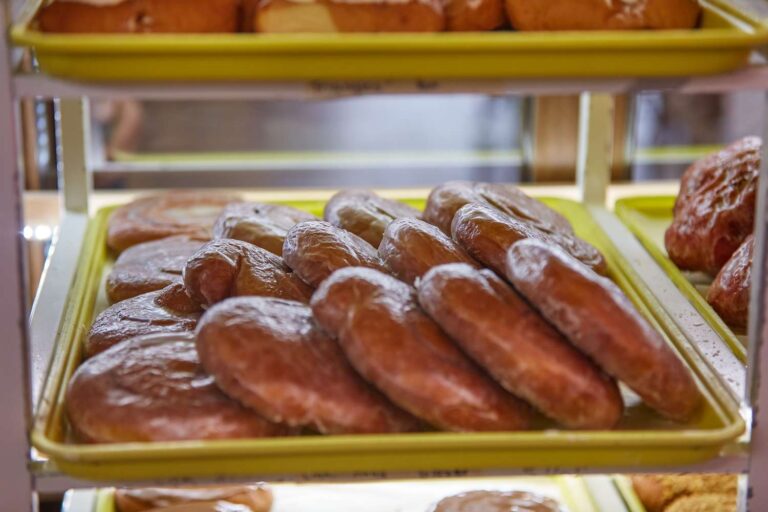 Tray of glazed donuts on bakery shelf.