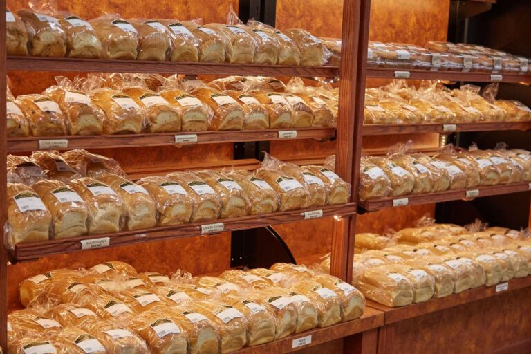 Shelves stocked with various packaged breads in bakery