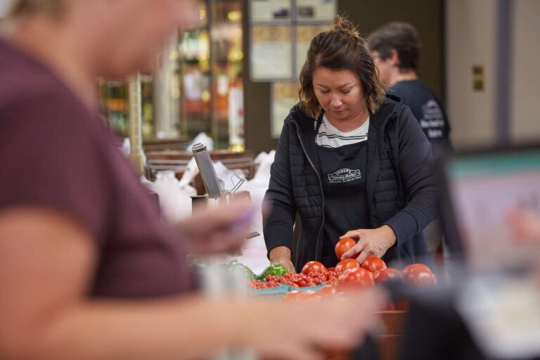 Woman sorting tomatoes at a market counter.