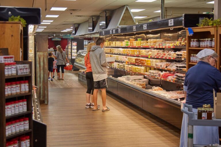 Shoppers selecting items in a grocery store aisle.