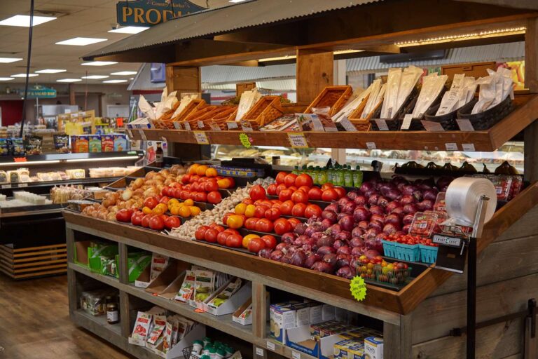 Supermarket produce section with various fruits and vegetables.