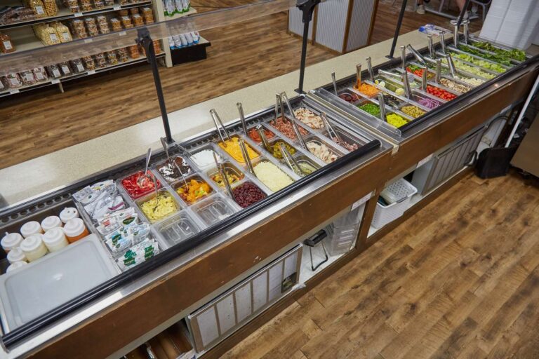 Salad bar with diverse fresh ingredients and toppings.